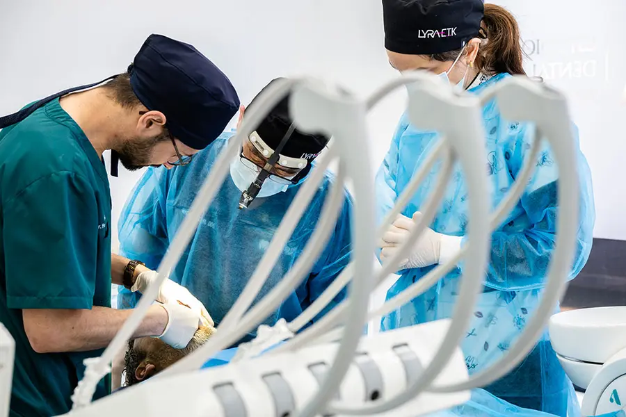 A surgeon with loupes and a headlight operating, the assistant opposite